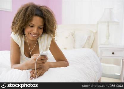 Teenage Girl Lying On Bed Using Mp3 Player
