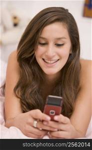 Teenage Girl Lying On Her Bed Using Mobile Phone
