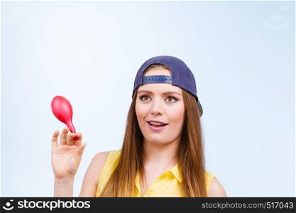 Teenage girl making funny silly faces. Young trendy woman in jeans cap holding red balloon.. Teenage girl with red balloon.