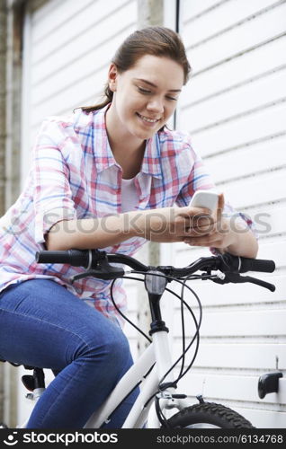 Teenage Girl On Bike Texting On Mobile Phone