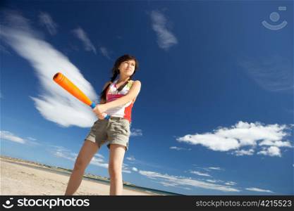 Teenage girl playing baseball on beach