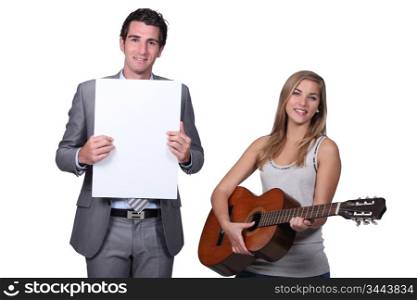 Teenage girl playing guitar teacher holding blank message board