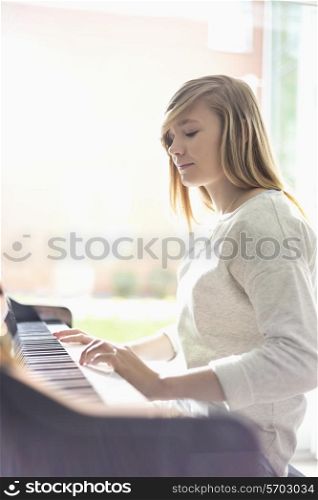Teenage girl playing piano at home