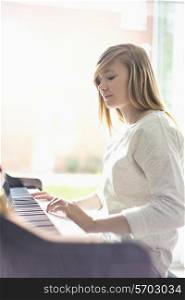 Teenage girl playing piano at home
