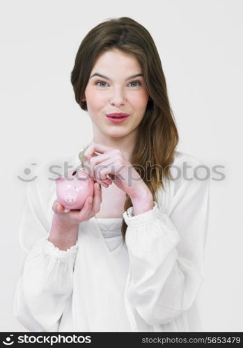 Teenage Girl Putting Money Into Piggy Bank