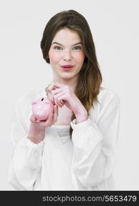 Teenage Girl Putting Money Into Piggy Bank