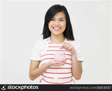 Teenage Girl Putting Money Into Piggy Bank