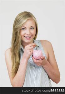 Teenage Girl Putting Money Into Piggy Bank