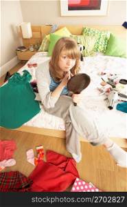 Teenage Girl Putting On Make Up In Untidy Bedroom