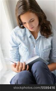 Teenage girl reading book sitting by window enjoy novel