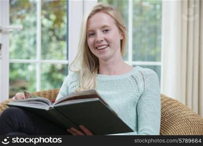Teenage Girl Relaxing And Reading Book At Home
