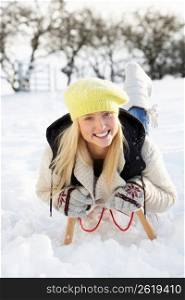 Teenage Girl Riding On Sledge In Snowy Landscape