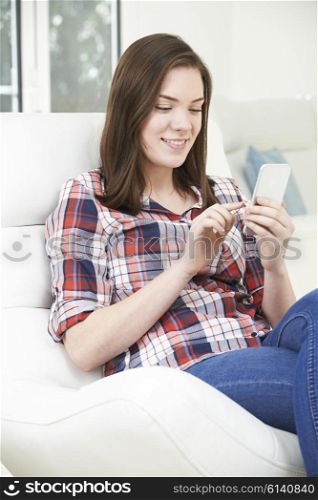 Teenage Girl Sending Text Message From Mobile Phone At Home