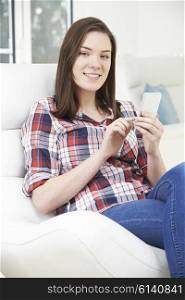 Teenage Girl Sending Text Message From Mobile Phone At Home