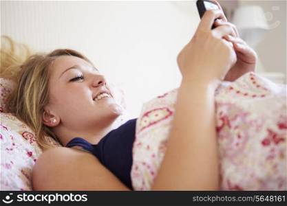 Teenage Girl Sending Text Message Whilst Lying In Bed