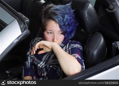 Teenage girl showing depression while sitting in driver side of car.