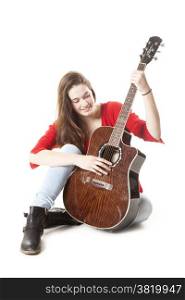 teenage girl sits and holds guitar in studio with white background