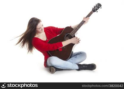 teenage girl sits and holds guitar in studio with white background
