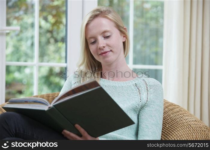 Teenage Girl Sitting At Home Reading Book