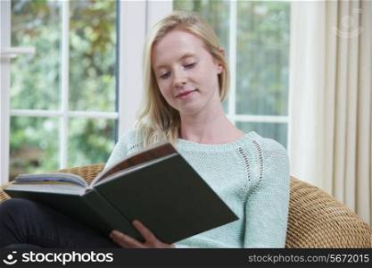 Teenage Girl Sitting At Home Reading Book
