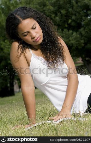 Teenage girl sitting in a lawn and reading a book