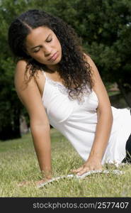 Teenage girl sitting in a lawn and reading a book