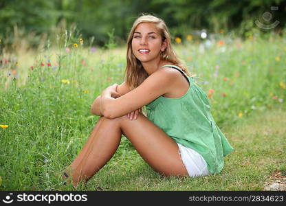 Teenage girl sitting in a wild flower meadow