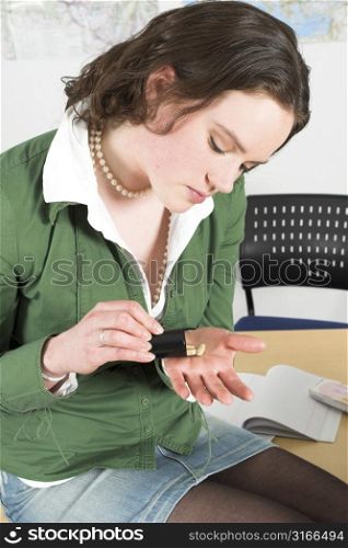 Teenage girl sitting on a desk in school shaking out some pills from a cannister