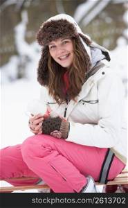 Teenage Girl Sitting On Sledge With Flask And Hot Drink