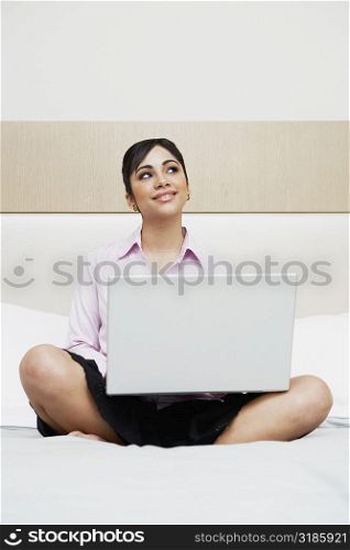 Teenage girl sitting on the bed with a laptop