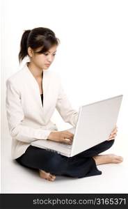 Teenage girl sitting on the floor and using a laptop