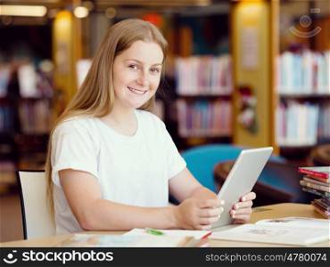 Teenage girl sitting with tablet in library. Teenage girl with tablet in library