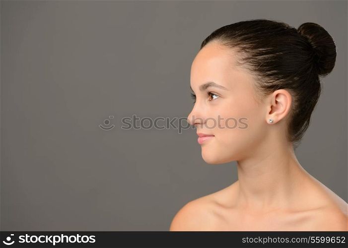 Teenage girl skin care cosmetics looking away side view on grey background
