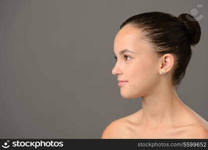 Teenage girl skin care cosmetics looking away side view on grey background