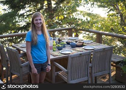 Teenage girl standing by patio dining table on a deck