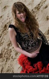 Teenage girl stands on sandy beach sticking her tongue out