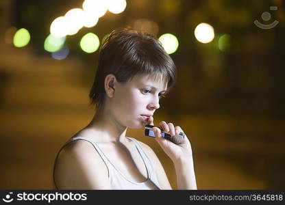 Teenage girl stands thinking with mobile phone in street