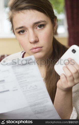 Teenage Girl Studying Mobile Phone Bill Looking Worried