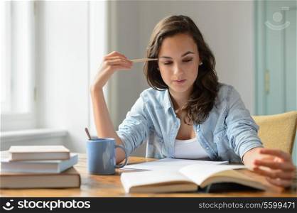 Teenage girl studying reading book at home concentrating looking down