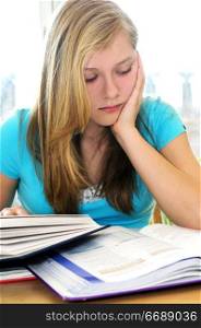 Teenage girl studying with textbooks looking unhappy