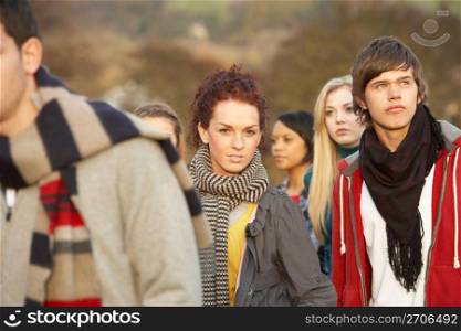 Teenage Girl Surrounded By Friends In Outdoor Autumn Landscape