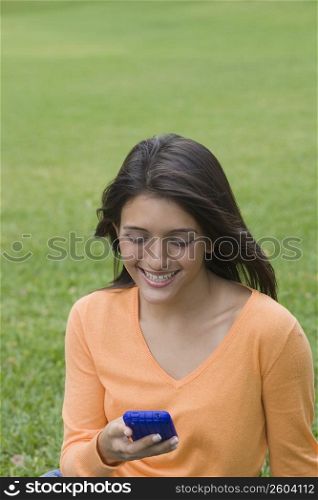 Teenage girl text messaging on a mobile phone in a park