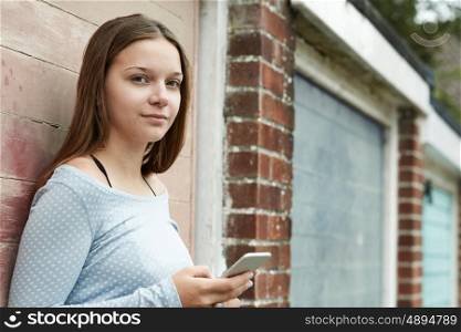 Teenage Girl Texting On Mobile Phone In Urban Setting