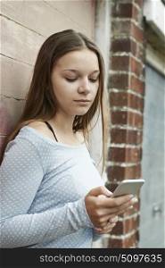 Teenage Girl Texting On Mobile Phone In Urban Setting