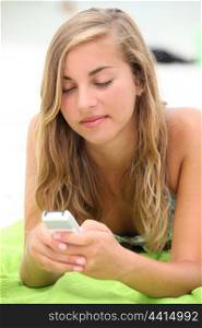 Teenage girl texting on the beach