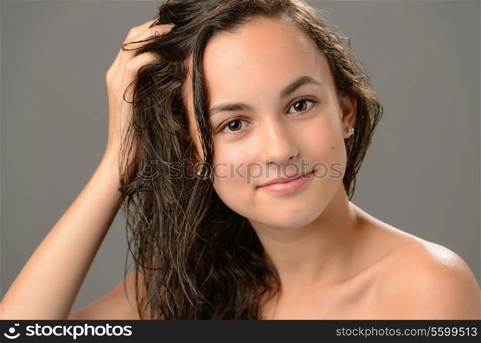 Teenage girl touch wet hair care cosmetics on gray background