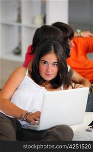 Teenage girl using a laptop at home with friends