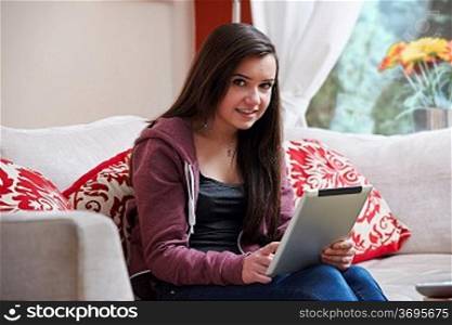 Teenage girl using a tablet pc while sitting at home