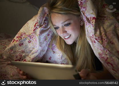 Teenage Girl Using Digital Tablet In Bed At Night