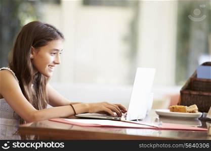 Teenage Girl Using Laptop On Desk At Home